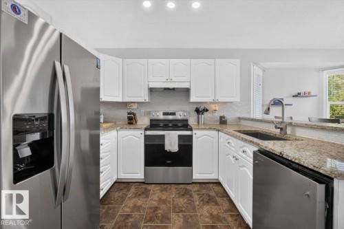 Kitchen featuring white cabinetry, granite countertops, stainless steel appliances, and a mosaic tile backsplash - 3907 33 Street, Edmonton, AB 