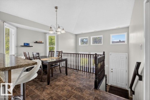 Open-concept dining area featuring tiled flooring, a vaulted ceiling, and multiple windows with white trim - 3907 33 Street, Edmonton, AB 