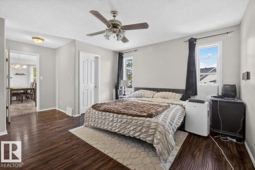 Bedroom featuring dark wood-finish flooring, light grey painted walls, and a ceiling fan with integrated lighting - 3907 33 Street, Edmonton, AB 