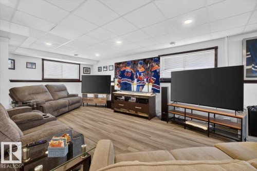 Finished room featuring wood-finish flooring, white walls, and a white grid ceiling with recessed lighting - 3907 33 Street, Edmonton, AB 