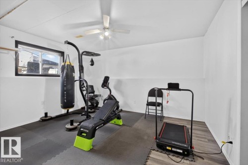 Versatile bonus room featuring a window with black trim, a ceiling fan with integrated lighting, and a blend of soft rubber flooring and wood-finish flooring - 3907 33 Street, Edmonton, AB 