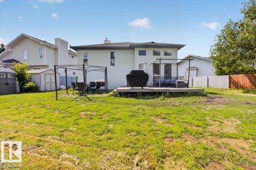 Expansive backyard featuring a large wooden deck, dual garden sheds, and a partial privacy fence - 3907 33 Street, Edmonton, AB 