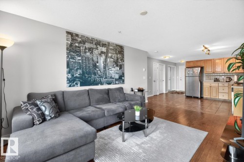 Open-concept living space featuring wood-finish flooring, recessed lighting, and a kitchen with light wood cabinetry and stainless steel appliances - 320 5005 165 Avenue, Edmonton, AB - Indoor Photo Showing Living Room