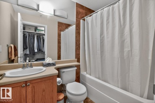 Bathroom featuring a built-in vanity with a wood-finish cabinet, a built-in toilet, and a combined shower-bathtub unit - 320 5005 165 Avenue, Edmonton, AB - Indoor Photo Showing Bathroom