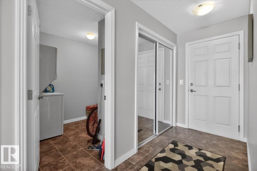 Entryway featuring tiled flooring, a paneled entry door, and mirrored closet doors - 320 5005 165 Avenue, Edmonton, AB - Indoor Photo Showing Other Room