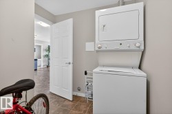 Integrated laundry area featuring a white stackable washer and dryer unit, tiled flooring, and neutral wall tones - 