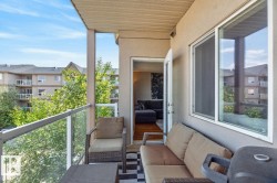 Private balcony featuring glass panel railings, textured exterior walls, and a white framed window - 