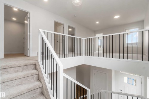 Carpeted staircase with white balusters and black spindles leading to an open landing - 19360 29 Avenue, Edmonton, AB 