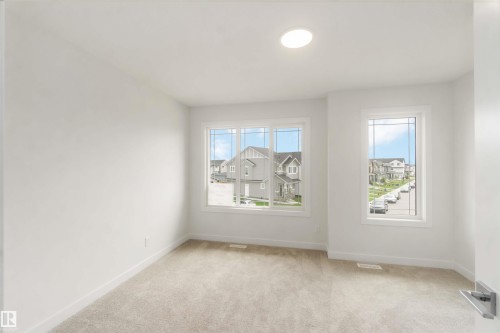 Bright room featuring light-colored carpeting, white baseboards, and a circular ceiling light fixture - 19360 29 Avenue, Edmonton, AB 