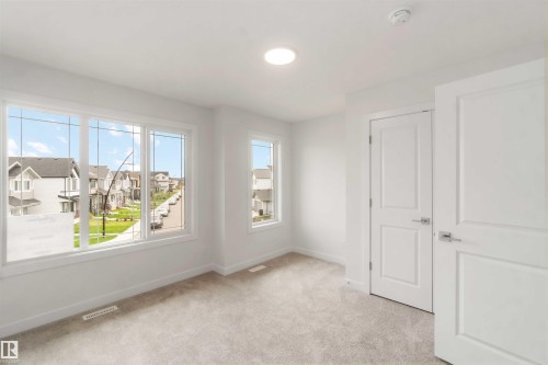 Bright room featuring multiple windows with white trim, light-toned carpeting, and a flush-mount ceiling light fixture - 19360 29 Avenue, Edmonton, AB 