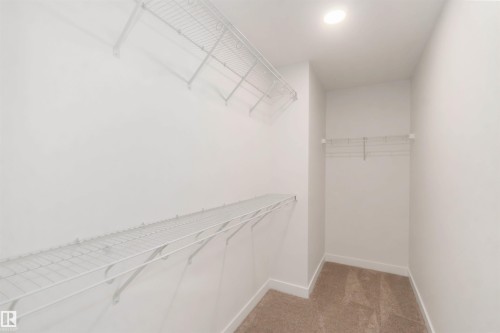 Walk-in closet with white wire shelving, white wire hanging rod, recessed lighting, and neutral tone carpeting - 19360 29 Avenue, Edmonton, AB 