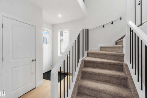 Inviting entryway featuring light wood-finish flooring and a white paneled door - 19360 29 Avenue, Edmonton, AB 