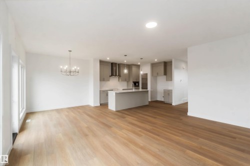 Open-concept living space featuring wood-finish flooring, a modern chandelier, and recessed lighting - 19360 29 Avenue, Edmonton, AB 