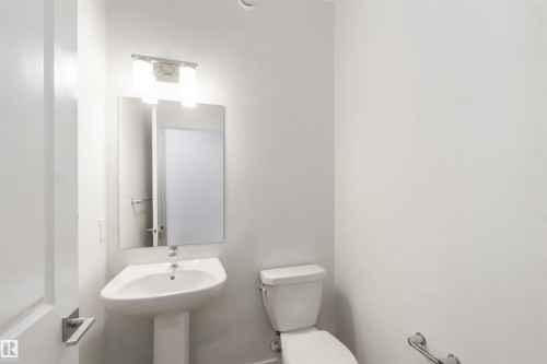Pedestal sink with a wall-mounted rectangular mirror and a two-light vanity fixture - 19360 29 Avenue, Edmonton, AB 