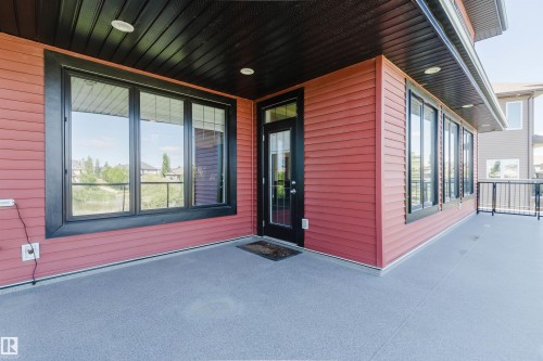 Covered outdoor patio area featuring a textured gray surface, red horizontal siding, and a dark ceiling with recessed lighting - 3438 West Landing Landing, Edmonton, AB 
