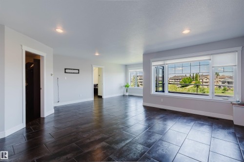 Spacious room featuring dark wood-finish tile flooring and light grey walls - 3438 West Landing Landing, Edmonton, AB 