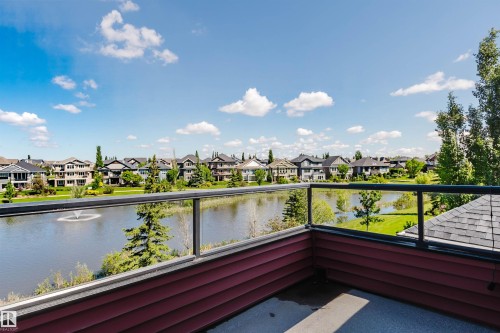 Balcony with clear glass railings overlooking a body of water with a fountain - 3438 West Landing Landing, Edmonton, AB 