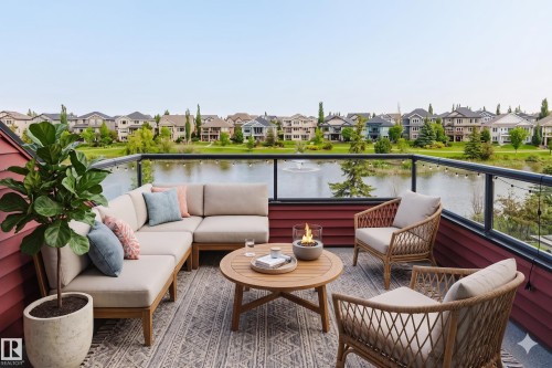 Expansive outdoor deck featuring a glass railing, water frontage, and a red siding exterior - 3438 West Landing Landing, Edmonton, AB 