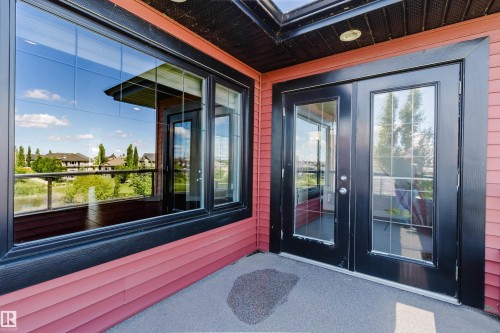 Exterior patio featuring red siding, black trim, and a dark aggregate surface - 3438 West Landing Landing, Edmonton, AB 