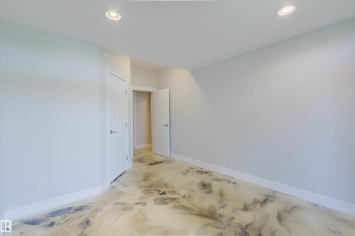 Spacious room featuring unique epoxy flooring with a marbled effect, recessed lighting, and white baseboards - 3438 West Landing Landing, Edmonton, AB 