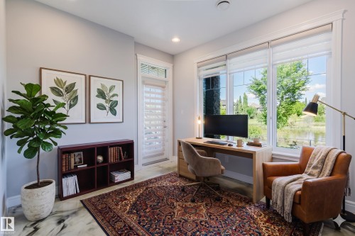 Bright interior space featuring expansive windows, wood-finish flooring, a built-in bookshelf, and recessed lighting - 3438 West Landing Landing, Edmonton, AB 
