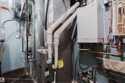 Utility area featuring a wall-mounted water heater, a furnace unit, extensive copper piping, and multiple ventilation ducts - 3438 West Landing Landing, Edmonton, AB 