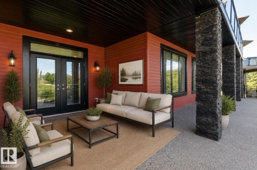 Covered patio featuring red horizontal siding and black-framed double glass doors - 3438 West Landing Landing, Edmonton, AB 