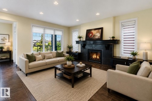 Spacious living area featuring a prominent fireplace with a dark mantel, recessed lighting, and wood-finish flooring - 3438 West Landing Landing, Edmonton, AB 