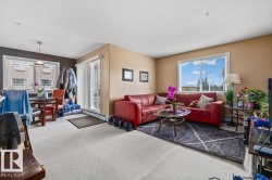 Open-concept living space featuring light-toned carpeting, neutral wall paint, and multiple windows for natural light - 