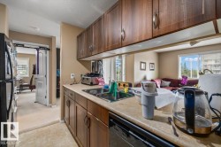 Kitchen featuring wood-finish cabinetry, neutral countertops, a double basin stainless steel sink, and a black built-in dishwasher - 