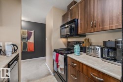 Galley kitchen featuring wood-finish cabinetry, laminate countertops, and essential black appliances including a built-in microwave and electric range - 
