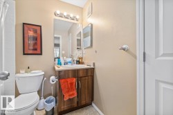 Bathroom featuring a wood-finish vanity with a light-toned countertop, a white toilet, and tile flooring - 
