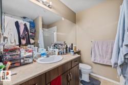 Bathroom vanity with an integrated sink, dark wood-finish cabinetry, and a light-toned countertop - 