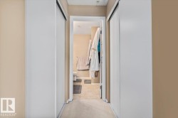 Hallway with light beige walls and neutral carpet, featuring two white sliding closet doors - 
