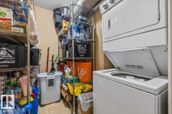 Dedicated utility area featuring a stackable washer and dryer unit, complemented by ample wire shelving for storage - 