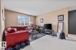 Living area featuring neutral wall tones, white trim, and a large window overlooking exterior residential structures - 