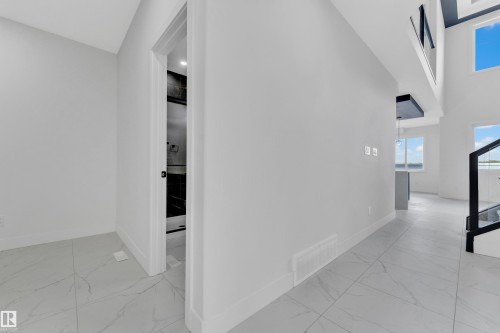 Open concept interior featuring high ceilings, white walls, and large format tile flooring - 4409 35 Street, Beaumont, AB - Indoor Photo Showing Other Room