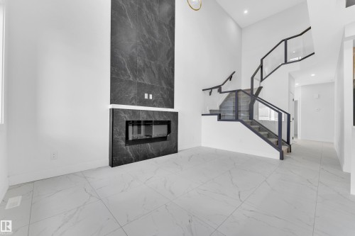 Contemporary fireplace featuring dark stone-finish surround and a linear electric insert - 4409 35 Street, Beaumont, AB - Indoor Photo Showing Other Room With Fireplace