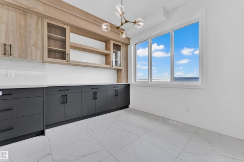 Built-in cabinetry featuring light wood-finish upper cabinets with glass fronts and open shelving, complemented by dark lower cabinetry with sleek hardware - 4409 35 Street, Beaumont, AB - Indoor