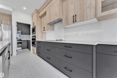Contemporary kitchen featuring two-tone cabinetry with wood-finish upper cabinets and dark gray lower cabinetry - 4409 35 Street, Beaumont, AB - Indoor Photo Showing Kitchen With Upgraded Kitchen