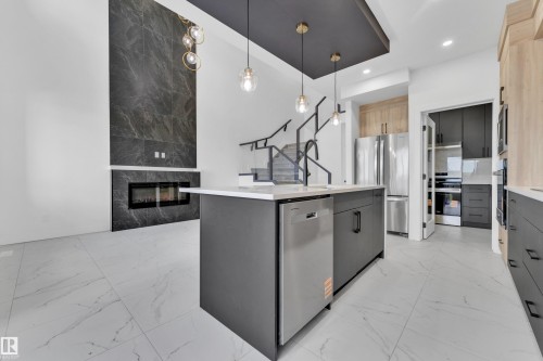 Contemporary kitchen island featuring a built-in dishwasher and sink with a matte black faucet, set against a backdrop of large format marble-look floor tiling - 4409 35 Street, Beaumont, AB - Indoor Photo Showing Kitchen With Upgraded Kitchen