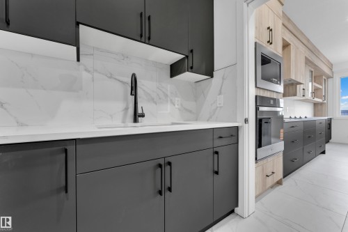 Modern kitchen featuring dark grey and light wood-finish cabinetry - 4409 35 Street, Beaumont, AB - Indoor Photo Showing Kitchen