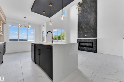 Open-concept living space featuring a kitchen island with a dark finish and a white countertop, complete with a contemporary black faucet - 4409 35 Street, Beaumont, AB - Indoor Photo Showing Kitchen