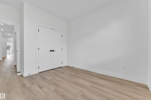 Room featuring wood-finish flooring, white walls, and a double-door closet with matte black hardware - 4409 35 Street, Beaumont, AB - Indoor Photo Showing Other Room