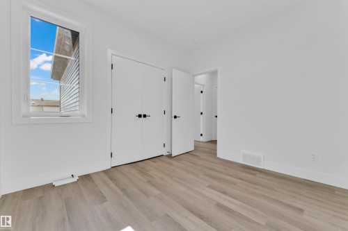 Bright interior room featuring a window, light wood-finish flooring, white walls, white baseboards, and white doors with matte black hardware - 4409 35 Street, Beaumont, AB - Indoor Photo Showing Other Room