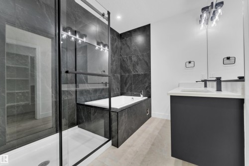 Modern bathroom featuring a dark tile surround, built-in soaking tub, and a glass-enclosed shower with a black frame - 4409 35 Street, Beaumont, AB - Indoor Photo Showing Bathroom