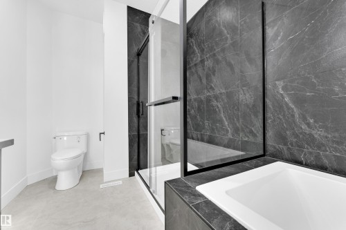 Contemporary bathroom featuring a built-in tub with dark tiled surround and a clear glass shower enclosure with black trim - 4409 35 Street, Beaumont, AB - Indoor Photo Showing Bathroom