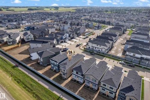 Aerial perspective of a developing residential community featuring a row of newly constructed homes with dark shingle roofs, light-colored siding, and multiple windows - 4409 35 Street, Beaumont, AB - Outdoor With View