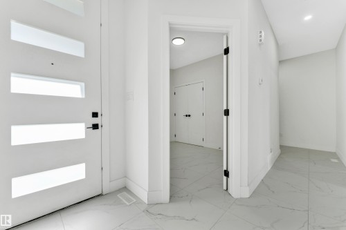 Entryway featuring a contemporary white door with frosted glass panels, matte black hardware, and large format tile flooring - 4409 35 Street, Beaumont, AB - Indoor Photo Showing Other Room