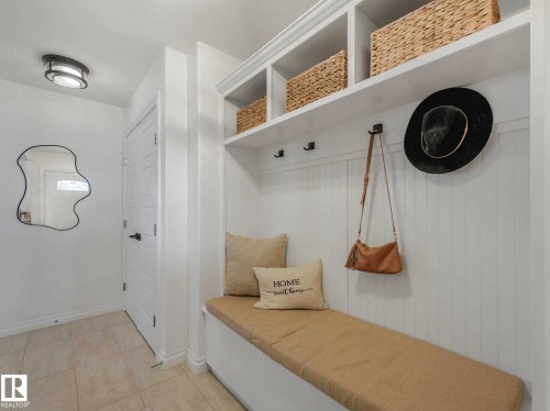 Built-in mudroom bench featuring upper shelving, beadboard backing, and integrated coat hooks - 162 Kirpatrick Way, Leduc, AB 